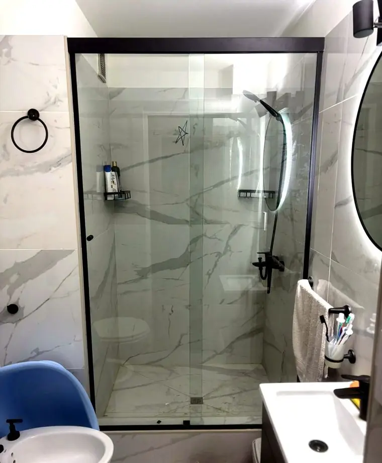 Baño terminado con porcelanato símil mármol y mampara de vidrio