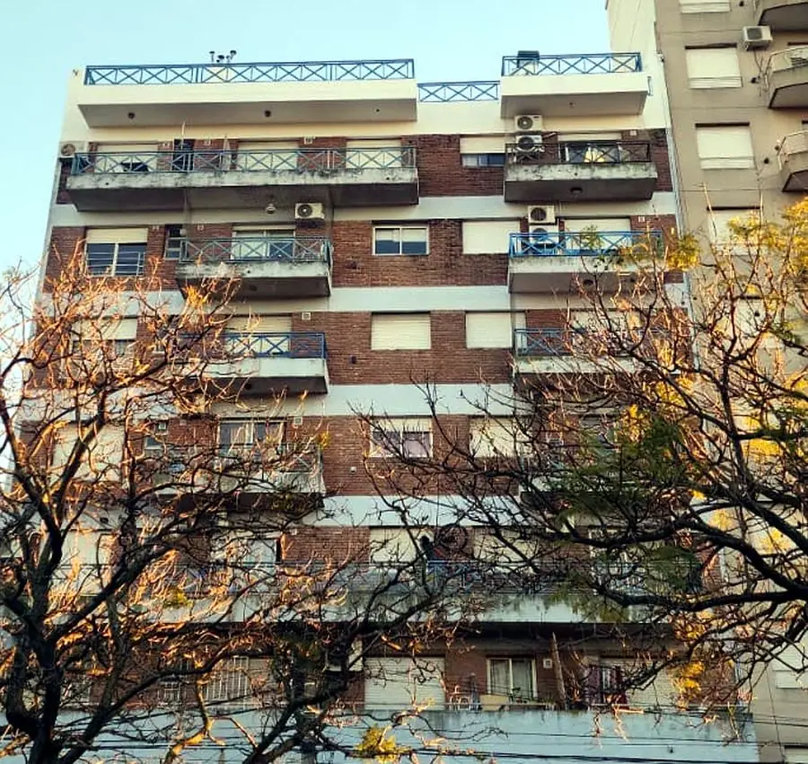 Edificio de departamentos de ladrillo con balcones y barandas azules