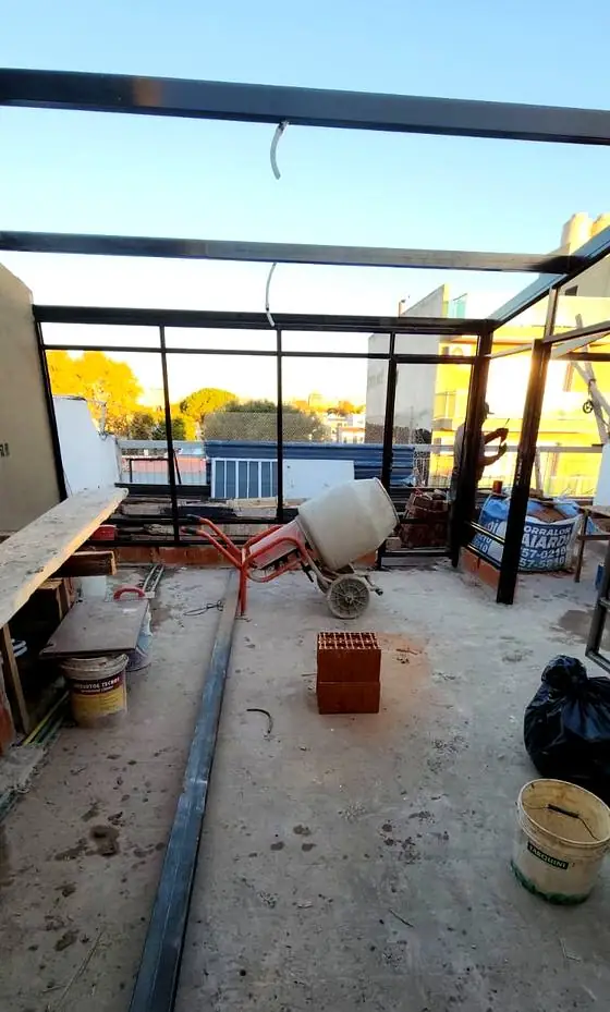Estructura metálica y cerramiento vidriado en construcción sobre terraza