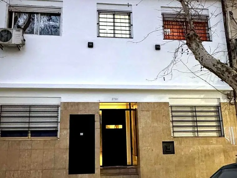 Frente de edificio reparado y pintado en blanco, con puerta de acceso renovada
