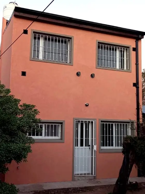 Frente de vivienda pintado en tono terracota con aberturas nuevas