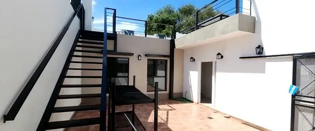 Patio terminado con escalera metálica, aberturas de aluminio negro y piso cerámico