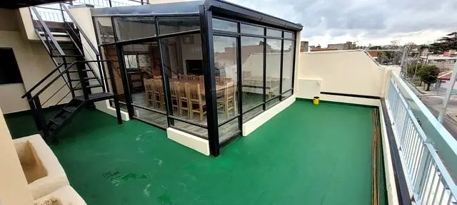 Terraza terminada con quincho de cerramiento vidriado, piso impermeabilizado y escalera metálica